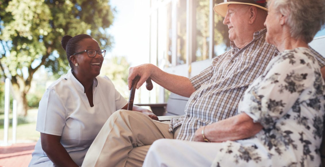 Senior couple with caregiver sitting outside